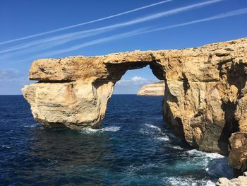 Rock formations by sea against blue sky