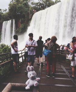 People standing by waterfall against trees