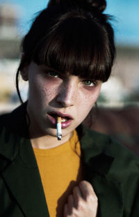 Close-up portrait of young woman holding sunglasses