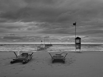 Deck chairs on beach against sky