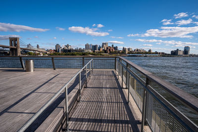 Bridge over river by buildings against sky