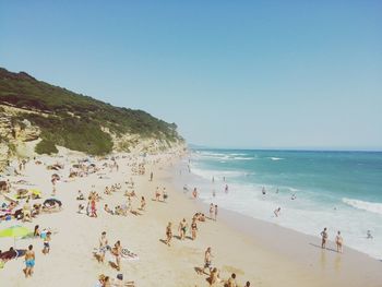 Panoramic view of people on beach against clear blue sky