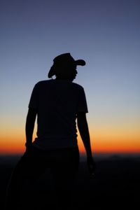 Rear view of silhouette man standing against clear sky during sunset