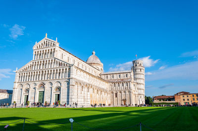 People visiting cathedral against blue sky during sunny day