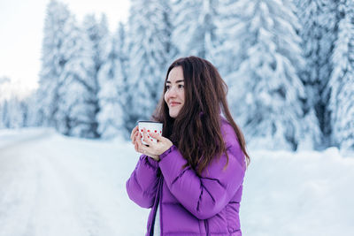 Woman drinking hot tea while on a road trip during winter.