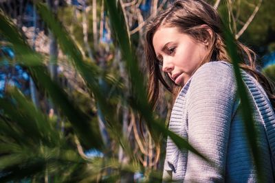 Close-up of woman looking away seen through plants