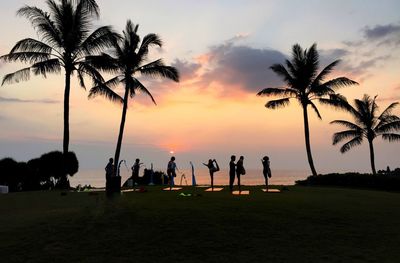 Silhouette people playing on beach against sky during sunset