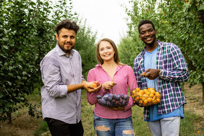 Portrait of smiling friends standing against plants