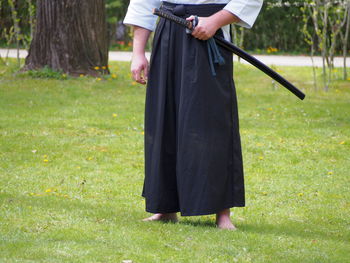 Low section of man with samurai sword on field