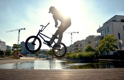 Man performing stunt while cycling over boardwalk during sunny day