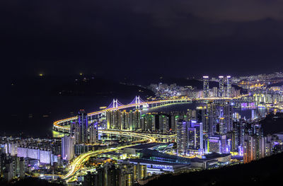 High angle view of illuminated bridge and buildings against sky at night