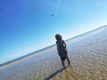 Man flying over sea against clear blue sky