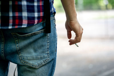 Midsection of man holding cigarette