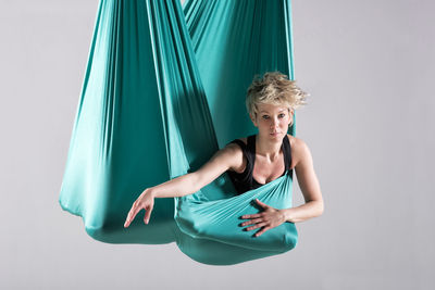 Portrait of aerialist performing on silk against wall