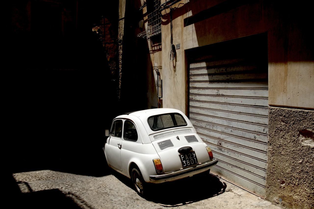 ABANDONED CAR ON STREET AGAINST BUILDING