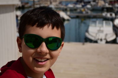 Portrait of smiling boy wearing sunglasses at harbor