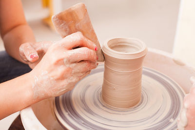 Hands shaping clay on pottery wheel