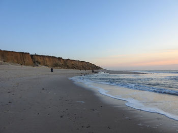 Scenic view of beach against clear sky during sunset