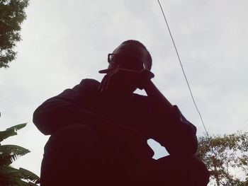 Low angle view of man holding camera against sky