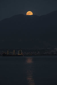 The moon rises behind the hills