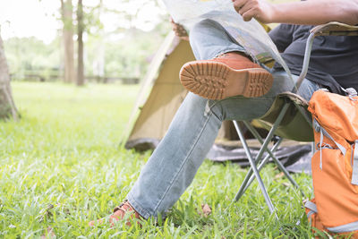 Low section of man sitting on chair at campsite