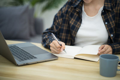 Midsection of woman using laptop on table