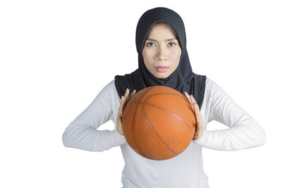 Portrait of woman in hijab playing basketball against white background