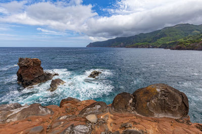 Scenic view of rocks in sea against sky