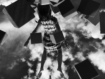 Low angle view of woman levitating amidst blocks against sky