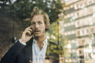 Businessman on cell phone behind windowpane