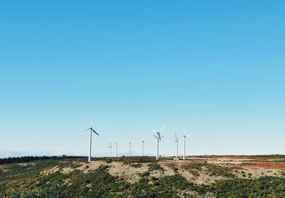 Wind turbines on field against clear sky