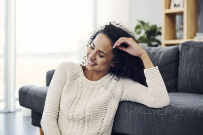 Young woman sitting on sofa at home