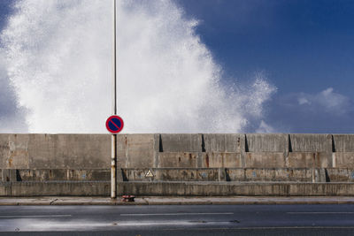 Road sign against wall in city