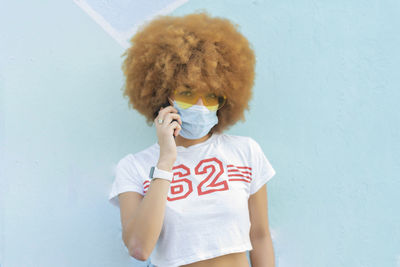 Woman with afro hair and face mask talking on her smartphone