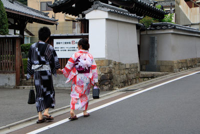 Rear view of women walking on street in city