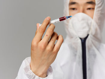 Midsection of doctor holding syringe against white background