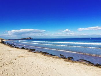 Scenic view of beach against blue sky