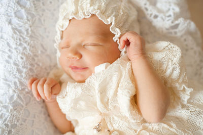 Smiling new born child girl sleeping in crib wear vitage hat and dress closeup top view. childhood.