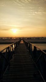 Pier over sea against sky during sunset