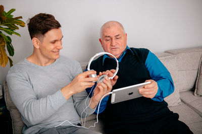 Grandfather with grandson holding headphones at home