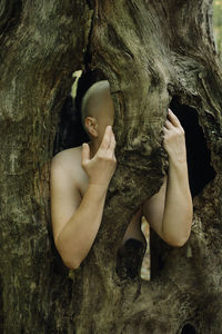 Young woman lying down on tree trunk