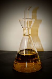 Close-up of glass bottle on table against wall