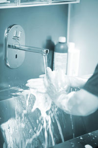 Cropped image of man washing hands at bathroom sink