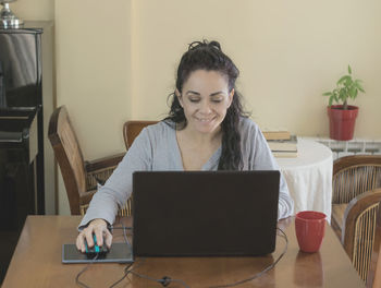 Young woman using mobile phone while sitting on table