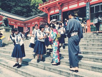 People outside temple against buildings in city