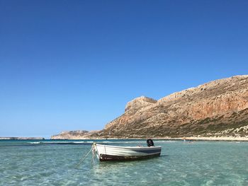 Sailboat in sea against clear blue sky