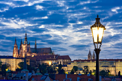 Illuminated buildings against cloudy sky