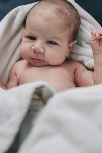 Portrait of cute baby boy lying down on bed