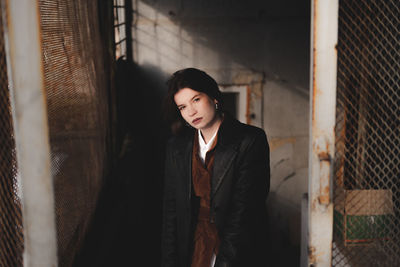 Portrait of beautiful young woman standing against wall