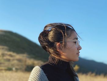 Portrait of young woman looking away against clear sky